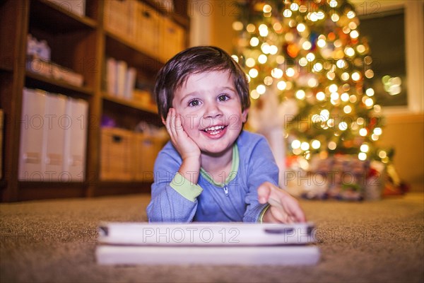 Caucasian boy using digital tablet by Christmas tree