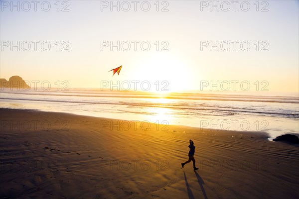 Caucasian woman flying kite on beach