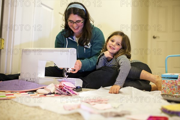 Caucasian mother teaching daughter to sew