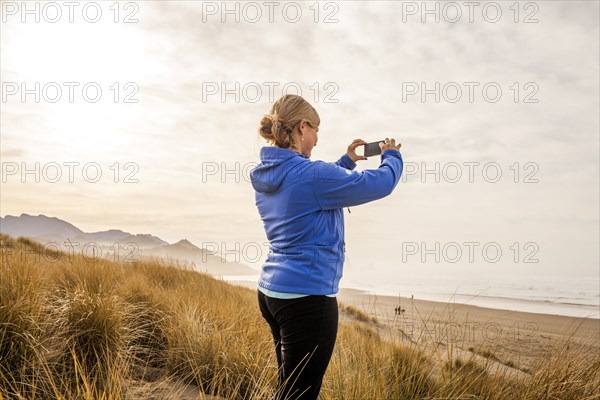 Caucasian woman taking pictures on beach