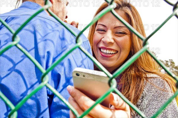 Hispanic woman with boyfriend using cell phone