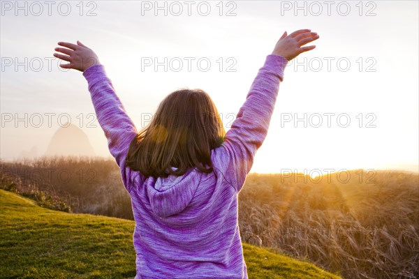 Caucasian girl cheering on rural cliffs