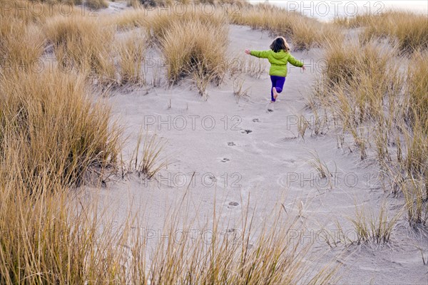 Caucasian girl running on sand dunes