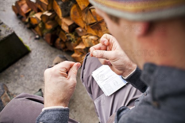 Man knotting thread outdoors