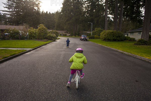 Caucasian children riding bicycles on suburban street