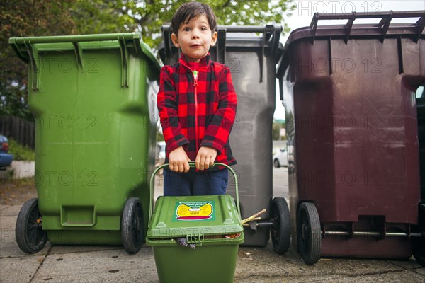 Mixed race boy carrying compost bin outdoors