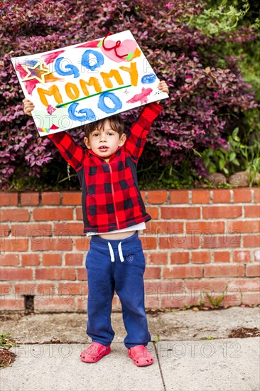 Mixed race boy holding Go mommy go sign