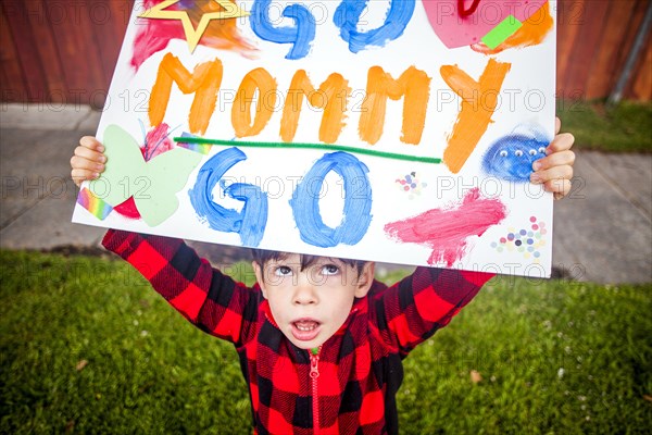 Mixed race boy holding Go mommy go sign