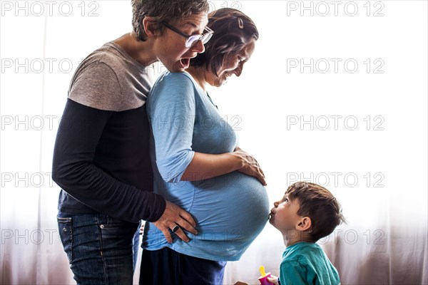 Lesbian couple with son standing by window