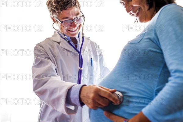 Doctor listening to womanÕs pregnant belly
