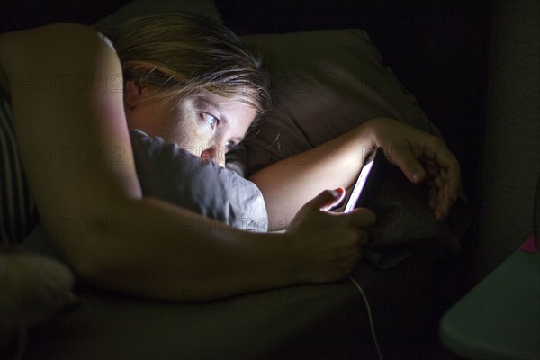 Caucasian woman using cell phone in bed