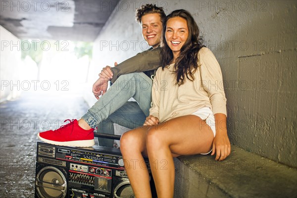 Caucasian couple listening to boom box in tunnel