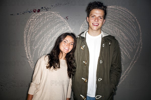 Caucasian couple smiling near chalk heart on wall