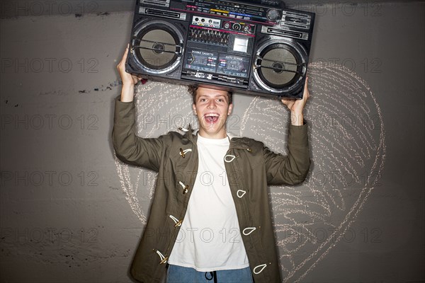 Caucasian man holding boom box near chalk heart on wall