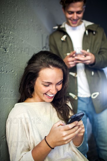 Caucasian couple using cell phones together in tunnel