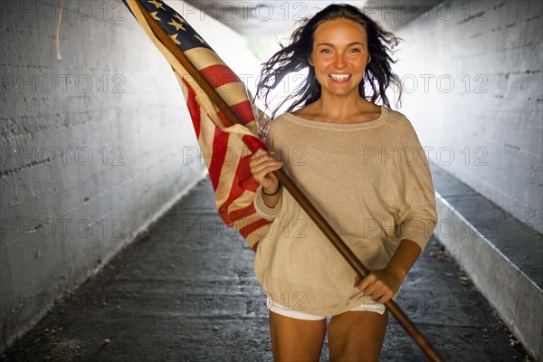 Caucasian woman carrying American flag in tunnel