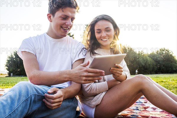 Caucasian couple using digital tablet together in park