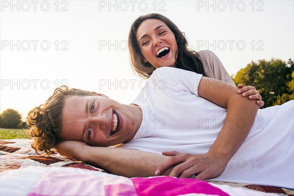 Caucasian couple relaxing on blankets in park