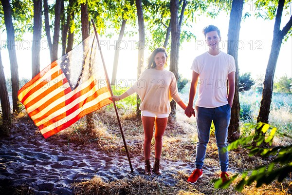 Caucasian couple holding American flag in park