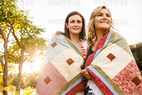 Caucasian teenage girls wrapped in blanket outdoors