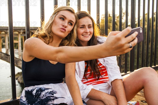 Caucasian teenage girls taking cell phone selfies