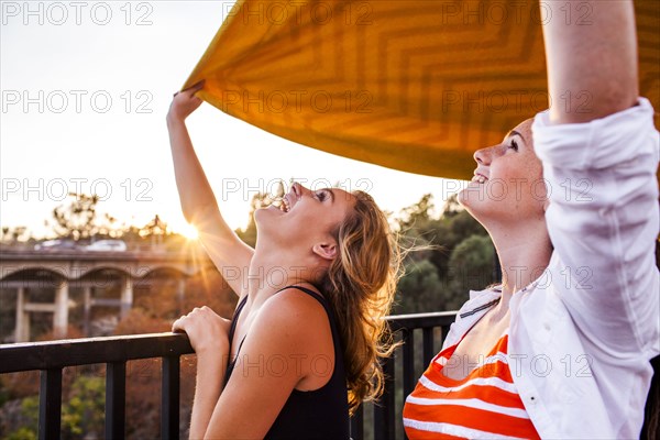 Caucasian teenage girls holding blanket on bridge