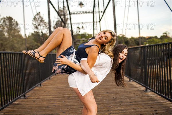 Caucasian teenage girls playing on wooden bridge