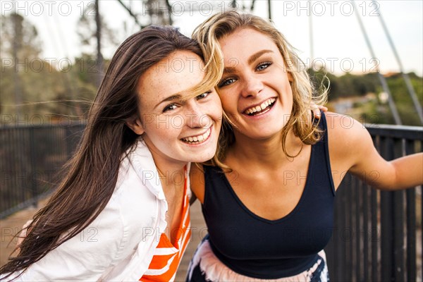 Caucasian teenage girls smiling on wooden bridge