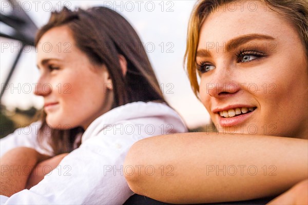 Caucasian teenage girls leaning on banister together