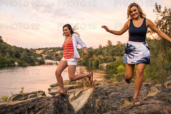 Caucasian teenage girls running on riverbank