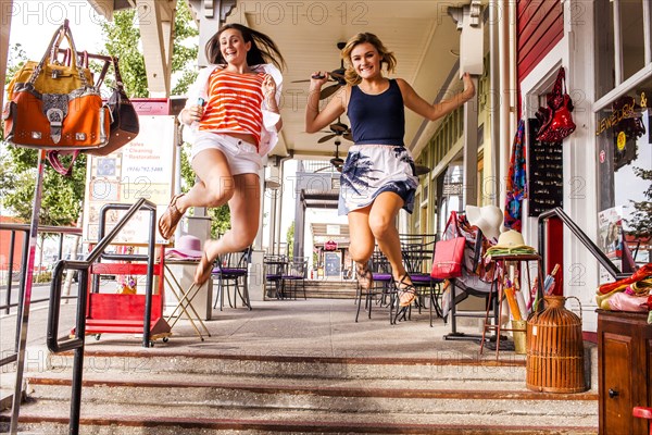 Caucasian teenage girls jumping for joy in city