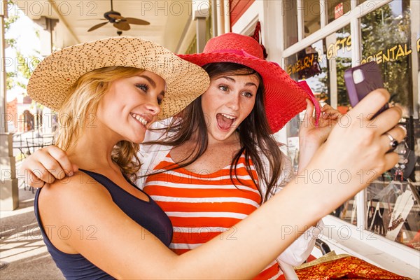 Caucasian teenage girls taking cell phone selfie in hats