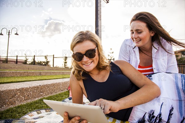 Caucasian teenage girls using tablet computer in park