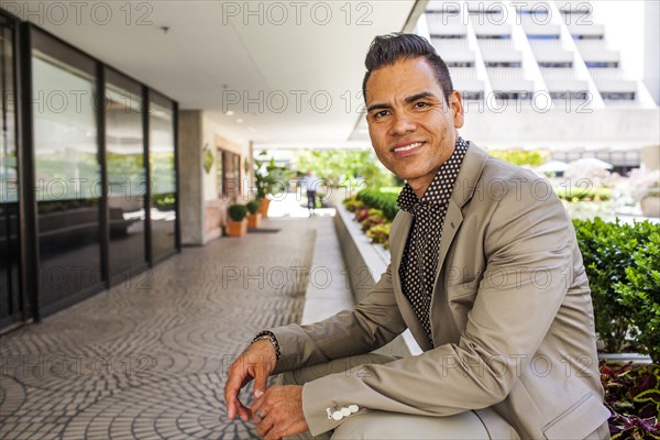 Hispanic businessman leaning over outdoor bench
