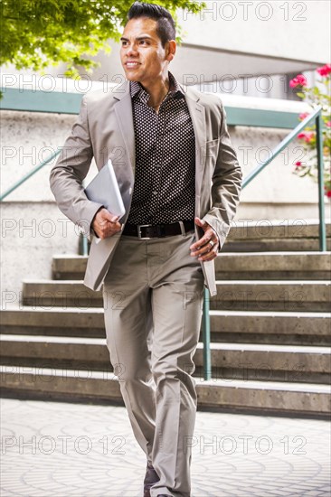 Hispanic businessman carrying digital tablet near staircase