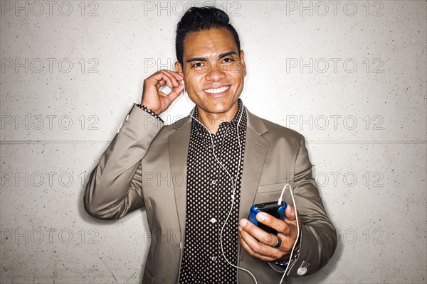 Hispanic businessman listening to earbuds with cell phone