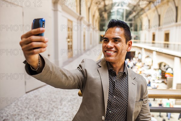 Hispanic businessman taking cell phone picture on upper level