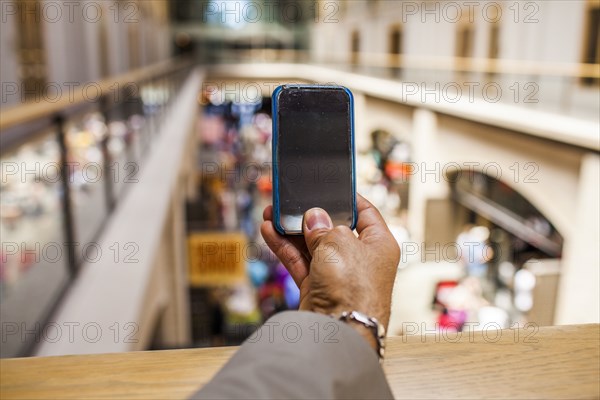 Hispanic businessman taking cell phone photograph from upper level