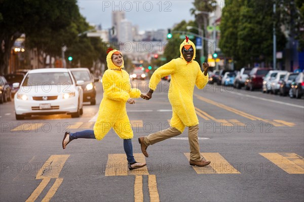 Couple in chicken costumes crossing city street