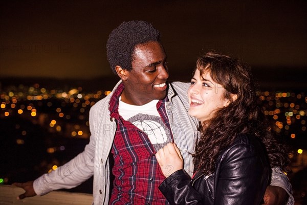 Couple hugging near scenic view of cityscape at night