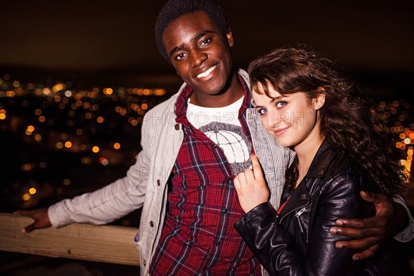 Couple hugging near scenic view of cityscape at night