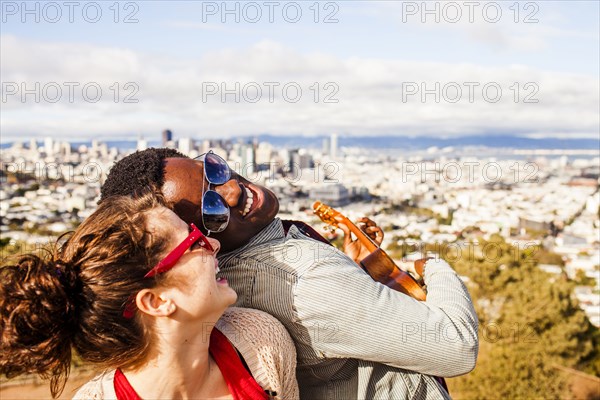 Couple playing ukulele near scenic view of cityscape