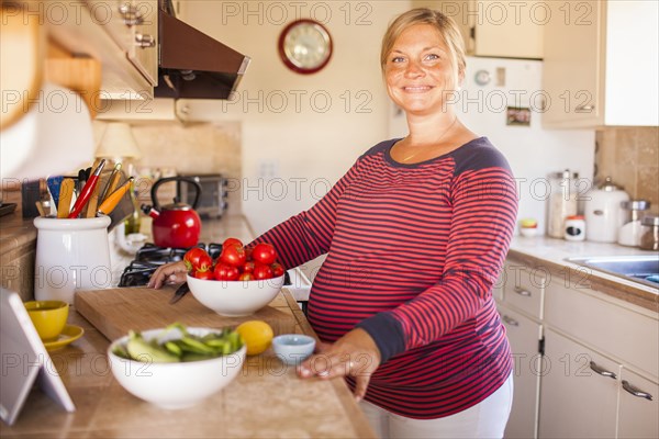Pregnant Caucasian mother cooking in kitchen