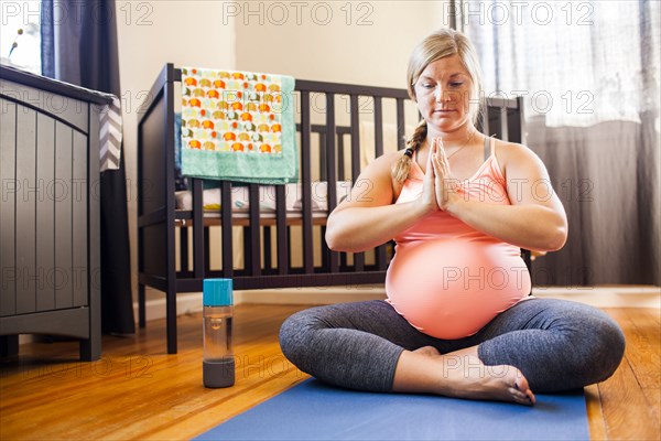 Pregnant Caucasian woman meditating in nursery