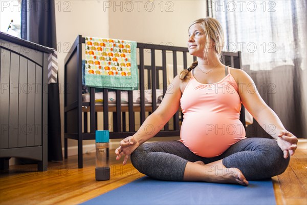 Pregnant Caucasian woman meditating in nursery