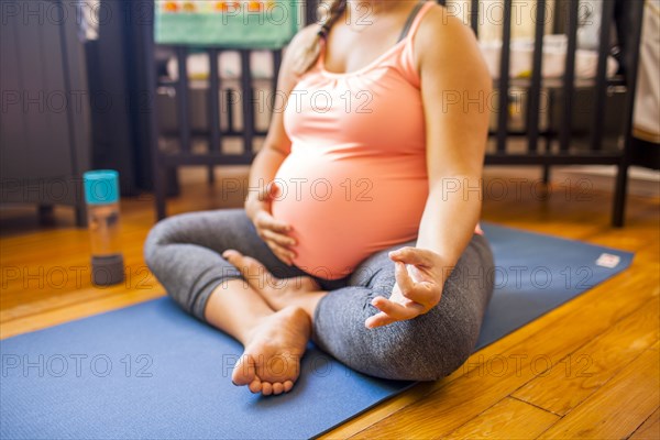 Pregnant Caucasian woman meditating in nursery