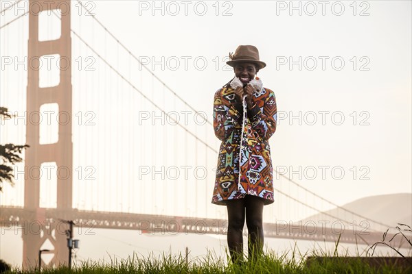 Black woman wearing colorful coat by Golden Gate Bridge