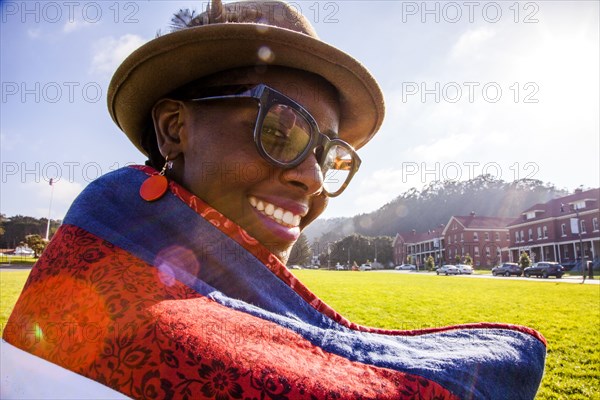 Black woman wrapped in blanket in urban park