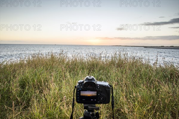 Close up of camera photographing sunset over ocean horizon