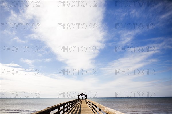 Wooden pier under blue sky over ocean